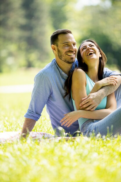 Afectuosa pareja joven sentada sobre la hierba verde en el parque