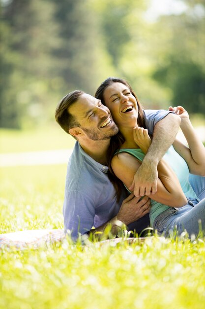 Afectuosa pareja joven sentada sobre la hierba verde en el parque