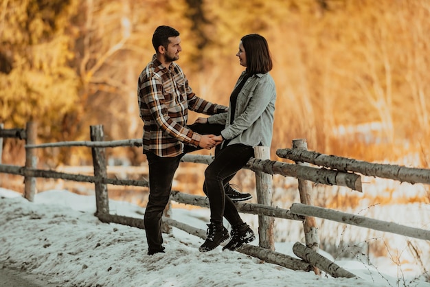 Afectuosa pareja tomándose de la mano e iniciando contacto visual contra el fondo del bosque invernal Enfoque selectivo