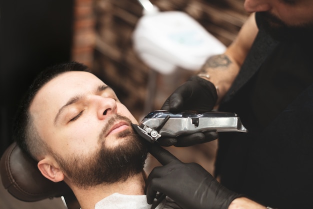 Afeitarse la barba en una barbería con una navaja de afeitar peligrosa. Peluquería Barba Cuidado. Secado, corte, corte de barba. Enfoque selectivo.