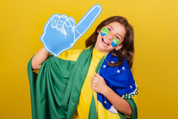 Aficionado al fútbol infantil caucásico brasileño con dedo de espuma celebrando y festejando los Juegos Olímpicos de la Copa Mundial