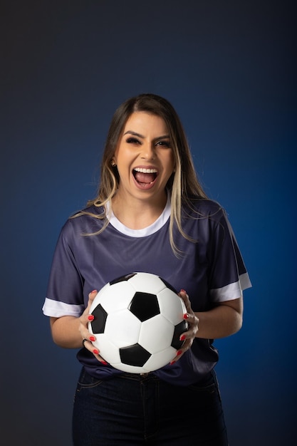 Aficionado al fútbol mujer animando a su club favorito y al equipo de fondo azul de la copa mundial