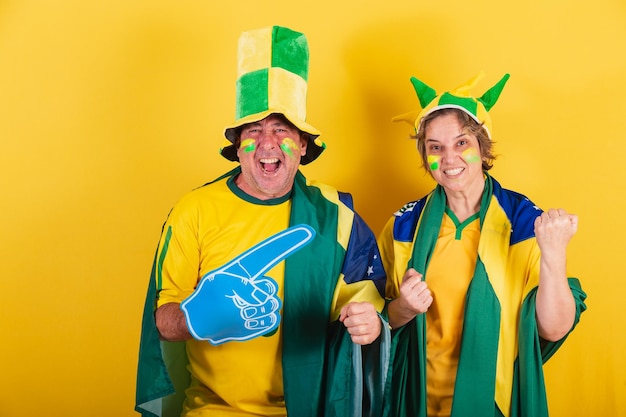 Aficionado al fútbol de pareja adulta de Brasil con bandera y sombrero Animando y festejando