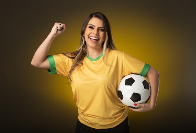 Aficionado brasileño Aficionado a la mujer brasileña celebrando en fútbol o partido de fútbol sobre fondo amarillo Colores de Brasil