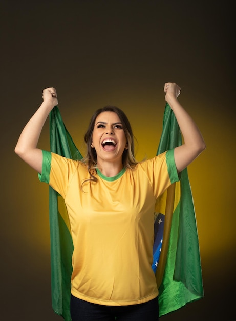 Aficionado brasileño Aficionado a la mujer brasileña celebrando en fútbol o partido de fútbol sobre fondo amarillo Colores de Brasil