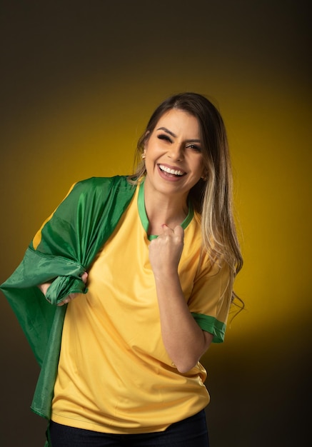 Aficionado brasileño Aficionado a la mujer brasileña celebrando en fútbol o partido de fútbol sobre fondo amarillo Colores de Brasil