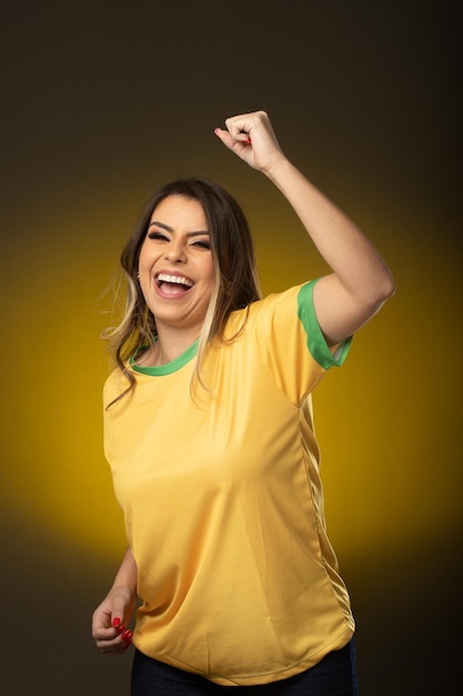 Aficionado brasileño Aficionado a la mujer brasileña celebrando en fútbol o partido de fútbol sobre fondo amarillo Colores de Brasil