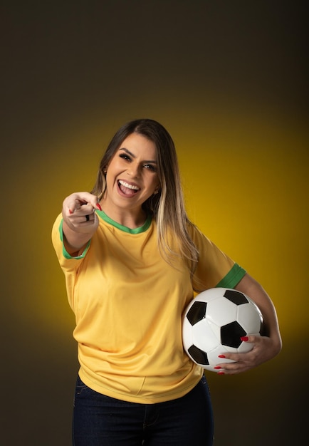 Aficionado brasileño Aficionado a la mujer brasileña celebrando en fútbol o partido de fútbol sobre fondo amarillo Colores de Brasil