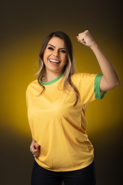 Aficionado brasileño Aficionado a la mujer brasileña celebrando en fútbol o partido de fútbol sobre fondo amarillo Colores de Brasil