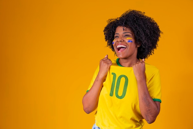 Aficionado brasileño con bandera brasileña en un retrato Aficionado brasileño celebrando fútbol o partido de fútbol sobre fondo amarillo Colores de la Copa del Mundo de Brasil