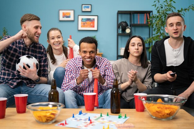 Aficionados al deporte multicultural alegre y chica encantadora animando y gritando fuerte mientras ve el deporte g