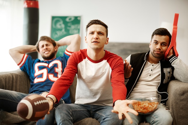 Aficionados al fútbol decepcionados viendo el partido con incredulidad