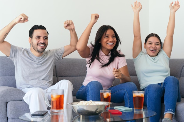 Foto aficionados al fútbol emocionados animando mientras ven la televisión jóvenes amigos están tomando bebidas y bocadillos en la fiesta están disfrutando del partido en casa