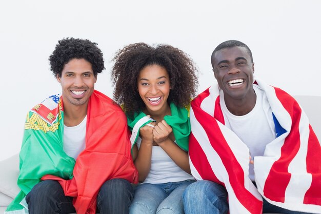 Aficionados al fútbol sentados en el sofá con banderas