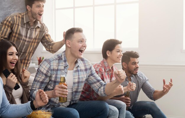 Aficionados al fútbol viendo fútbol en la televisión y celebrando la victoria en casa