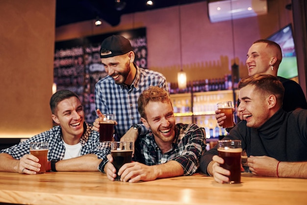 Aficionados al fútbol viendo la televisión Grupo de personas juntas en el interior del pub se divierten los fines de semana