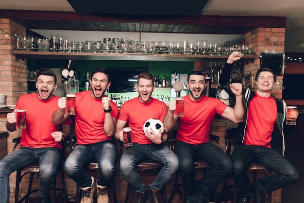 Aficionados a los deportes sentados en fila en el bar deportivo