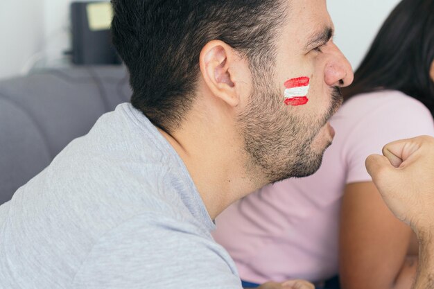 Aficionados peruanos viendo un partido de fútbol por televisión en casa