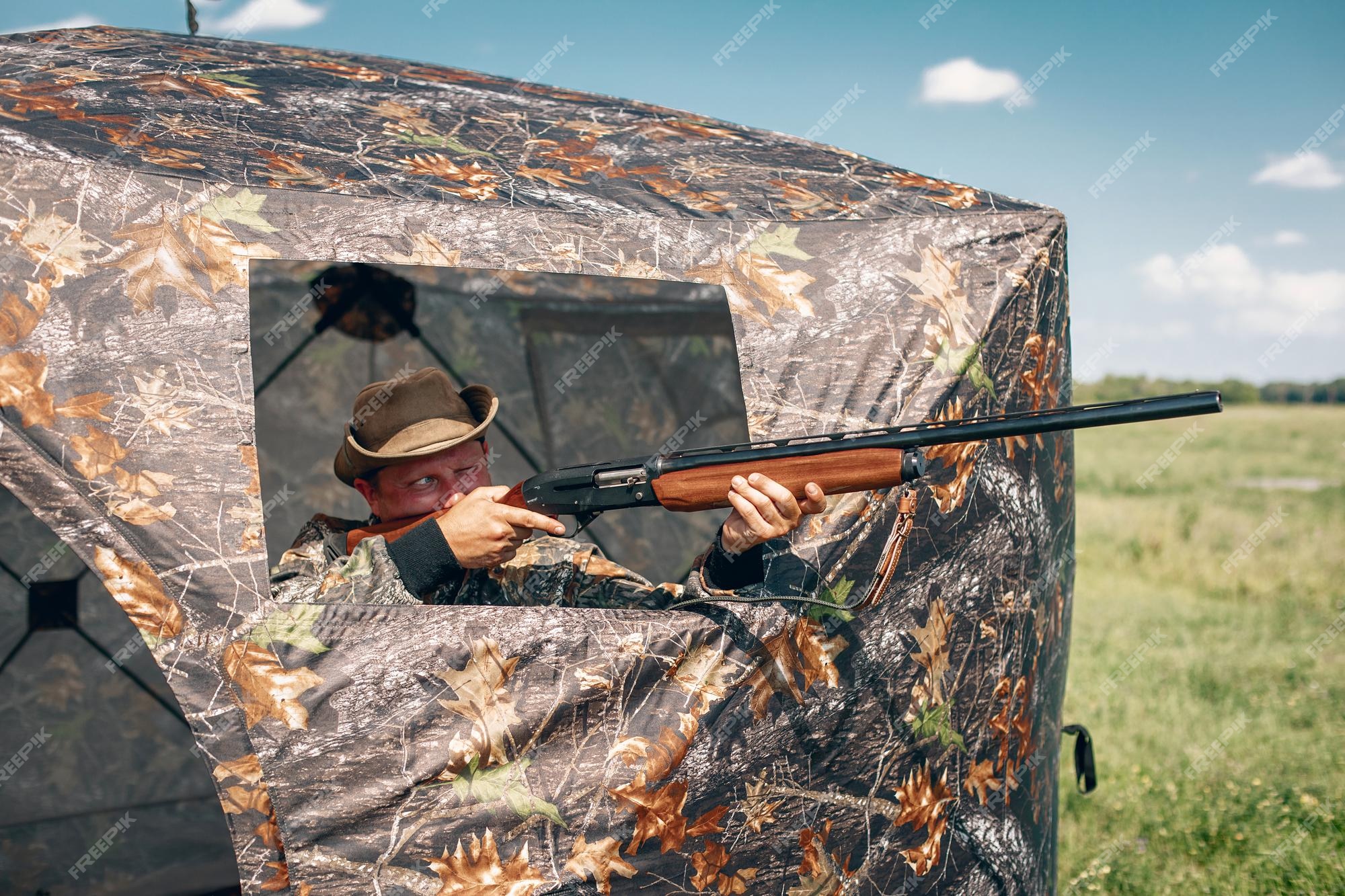 O caçador mira com um rifle. um homem camuflado está se preparando