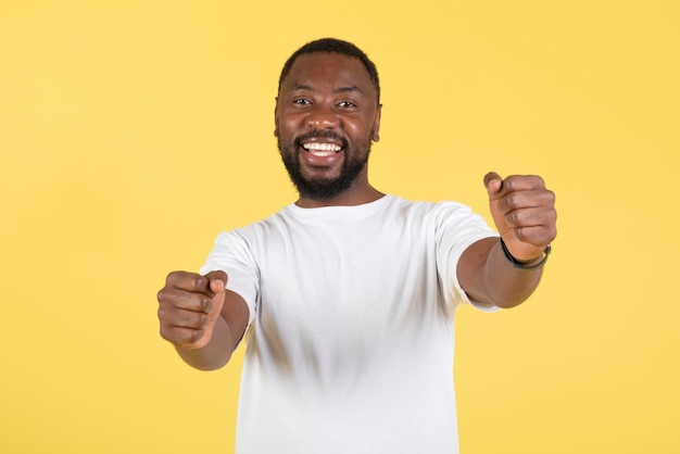 Africano segurando roda invisível fingindo dirigir carro fundo amarelo