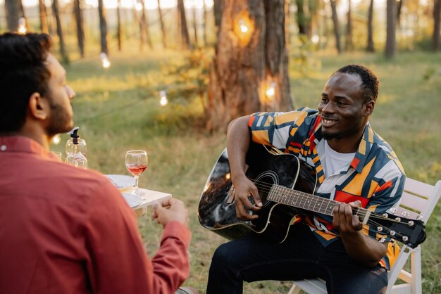 Un africano toca la guitarra para un indio que bebe vino y canta.