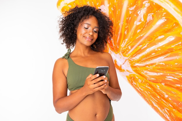 africano en un traje de baño verde y gafas tiene un colchón de natación