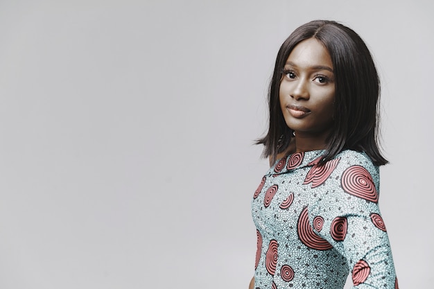 Afrikanerin in einem Studio. Weiße Wand. Frau in einem blauen Kleid.