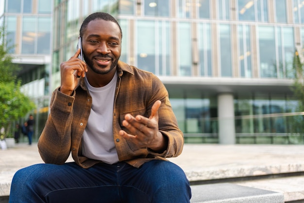 Afrikanisch-amerikanischer Mann spricht mit dem Smartphone auf der Straße in der Stadt, Mann im Freien mit Handy-Chat