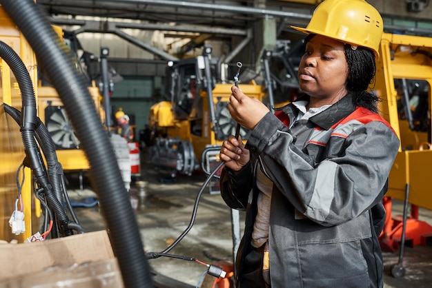 Afrikanische Arbeiterin in Uniform, die während ihrer Arbeit im Lager Drähte an Geräte anschließt