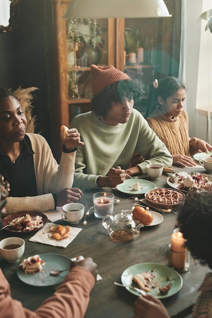 Afrikanische Familie sitzt am Esstisch, isst hausgemachten Kuchen und trinkt Tee während einer Familienveranstaltung