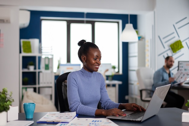 Afrikanische Frau, die am Laptop schreibt, konzentriert, um wichtige Fristen zu beenden