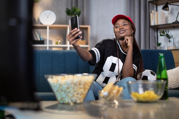 Afrikanische Frau, die während des Fußballspiels ein Selfie auf dem Smartphone macht