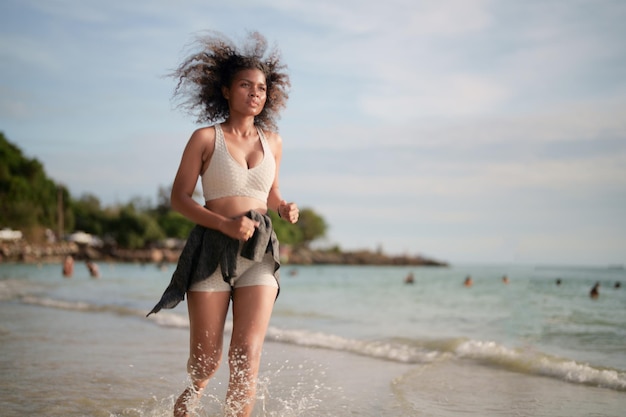 Afrikanische Frau im Sport-BH läuft am Strand für Outdoor-Training Portrait sexy asiatische afrikanische Dame bereitet sich auf Fitness am Strand vor
