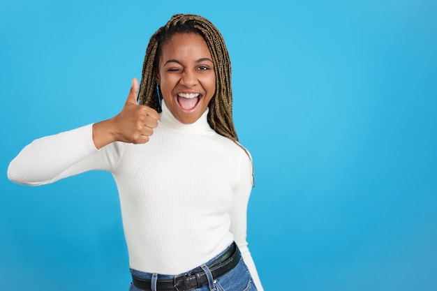 Afrikanische Frau zwinkert, während sie positiv mit dem Daumen nach oben gestikuliert