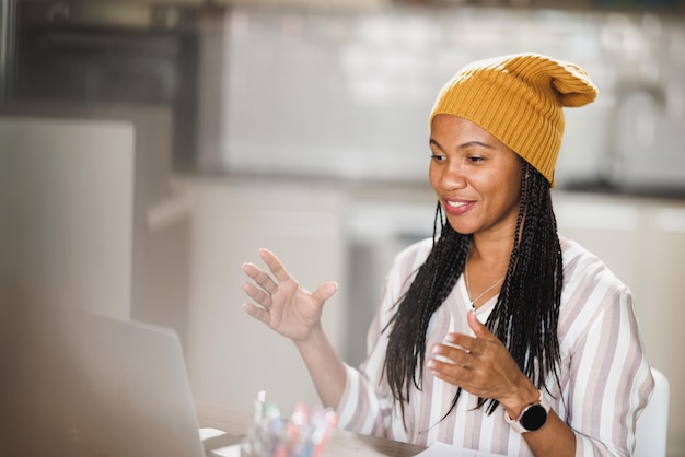 Afrikanische Geschäftsfrau benutzt einen Laptop und hält Online-Meetings ab, während sie von ihrem Heimbüro aus arbeitet.