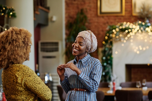 Afrikanische glückliche Frau, die mit ihrem Freund spricht und während des Treffens im Restaurant lächelt