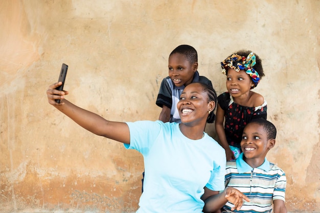 Afrikanische junge glückliche und gute alleinerziehende Mutter, die Spaß mit ihren Kindern hat und Selfie-Fotos auf der Smartphone-Kamera macht.