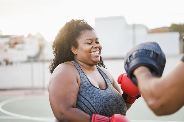 Afrikanische kurvige Frau und Personal Trainer beim Boxtraining im Freien Konzentrieren Sie sich auf das Gesicht