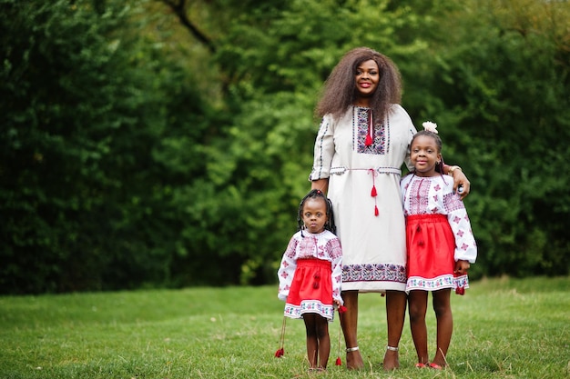 Afrikanische Mutter mit Töchtern in traditioneller Kleidung im Park.