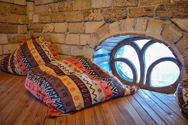 Afrikanische Puffs liegen in der Ecke auf einem Holzboden am Fenster mit einem ungewöhnlichen Gitter