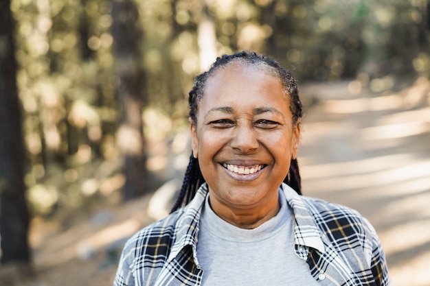 Afrikanische Seniorin lächelt vor der Kamera im Freien im Wald - Fokus auf Gesicht