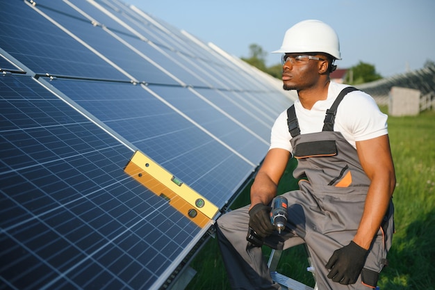 Afrikanischer amerikanischer Ingenieur, der Solarzellenpanele instandhält, Techniker, der im Freien am Bau einer ökologischen Solarfarm arbeitet, Konzept für erneuerbare saubere Energietechnologie