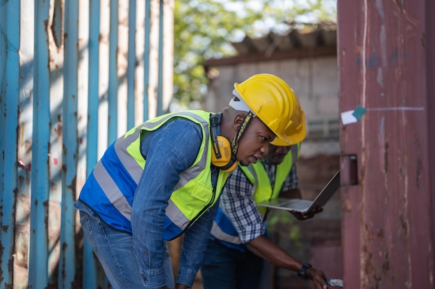 Afrikanischer Arbeiter Ingenieur Techniker mit Laptop zum Prüfen und Inspizieren von Containern vor Ort