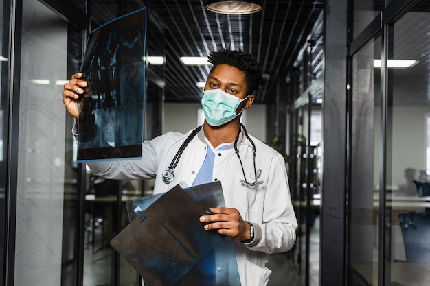 Afrikanischer Arzt untersucht Röntgenbilder in einer medizinischen Klinik Schwarzer Student in medizinischer Maske studiert und betrachtet ct-Scans