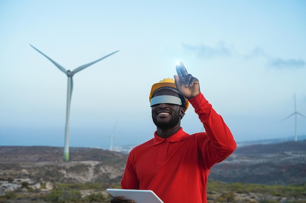 Afrikanischer Ingenieur nutzt futuristische Virtual-Reality-Brille bei der Arbeit auf einer Windmühlenfarm. Fokus auf Gesicht