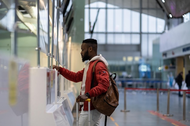 Afrikanischer junger Mann, der Dokumente am Check-in-Schalter in der Grenzkontrolle des Flughafens zeigt