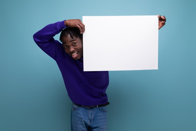 Afrikanischer junger Mann im blauen Sweatshirt hält Papierplakat mit Attrappe in der Hand
