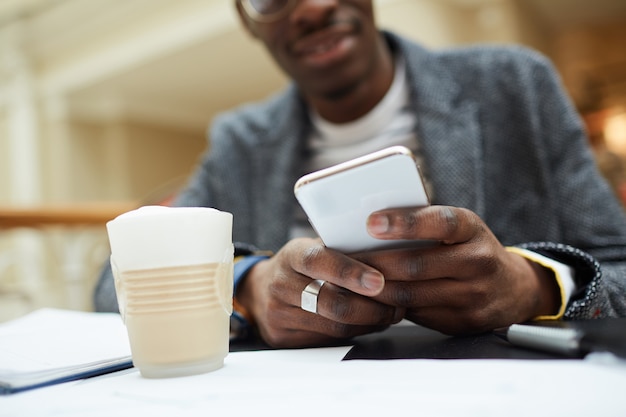 Afrikanischer Mann, der Smartphone hält