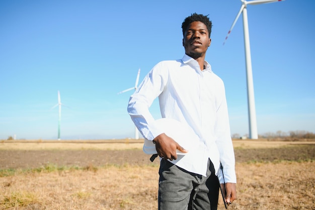 Afrikanischer Mann des Ingenieurs, der mit Windkraftanlage steht