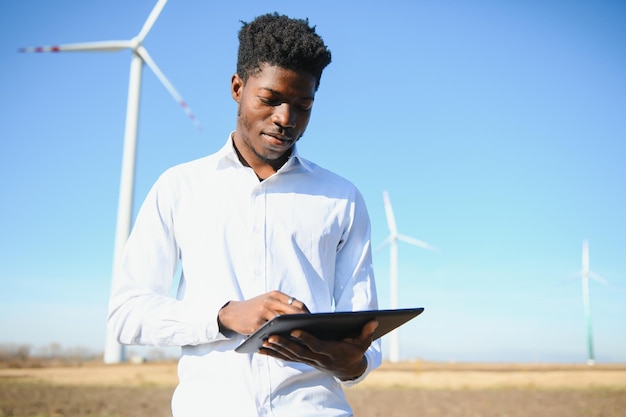 Afrikanischer Mann des Ingenieurs, der mit Windkraftanlage steht